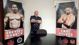 Jorge Fe posa entre la foto de dos de sus empleados.