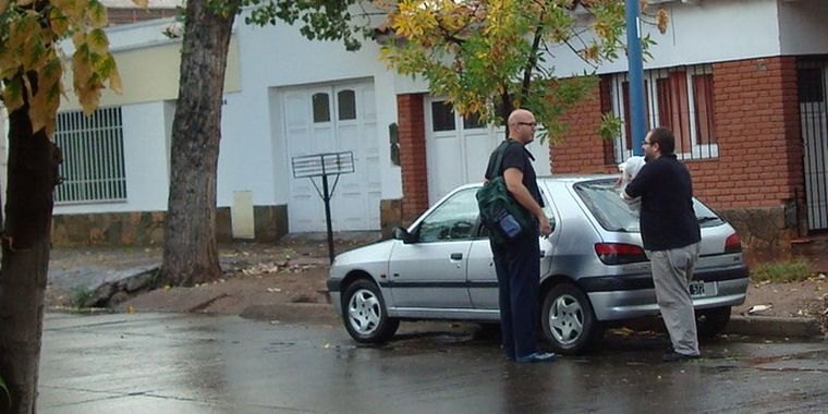 Un vecino de Godoy Cruz comenta la granizada mientras acaba de retirar un cobertor que puso de emergencia sobre su vehículo. Foto: Atahualpa Acosta