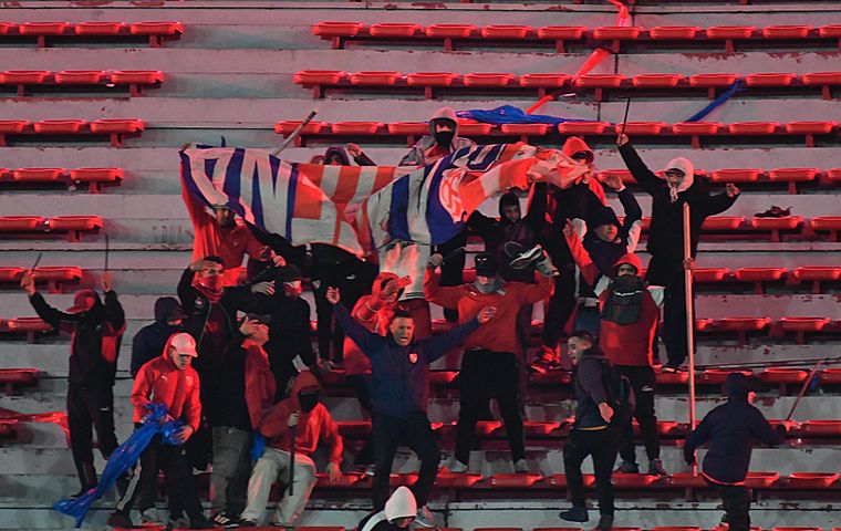 Los hinchas de Independiente exhiben una bandera del conjunto chileno. Fue luego de que la barra irrumpió en el sector visitante.