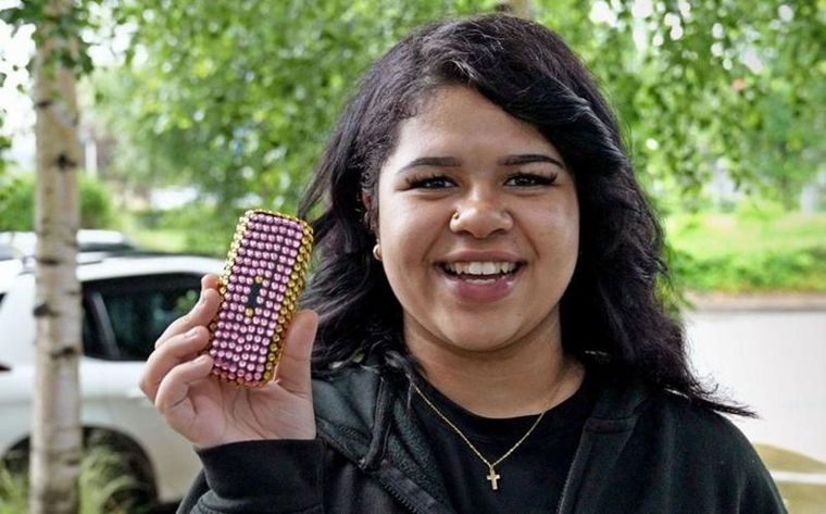 Grace con su teléfono básico adornado con joyas de plástico. Foto: BBC / KRISTIAN JOHNSON