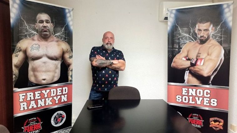 Jorge Fe posa entre la foto de dos de sus empleados.