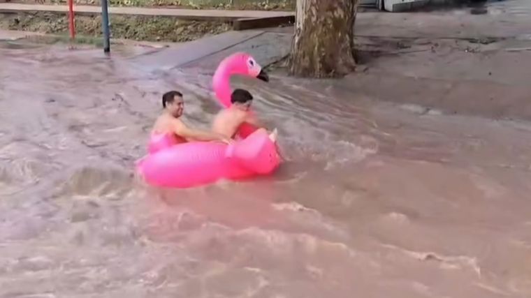 Dos jóvenes se divierten durante la tormenta en un inflable.