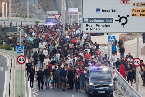 Agentes de policía y soldados españoles escoltan a un numeroso grupo de migrantes en Ceuta hasta la frontera para devolverlos a Marruecos.