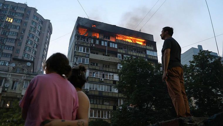 Un habitante de Kyiv observa un edificio de apartamentos que se incendia después de un ataque.