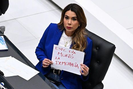 La diputada opositora de ARENA, Marcela Villatoro, con un cartel que dice "Hoy murió la democracia" durante una sesión plenaria del Congreso en San Salvador. La diputada opositora de ARENA, Marcela Villatoro, con un cartel que dice "Hoy murió la democracia" durante una sesión plenaria del Congreso en San Salvador.