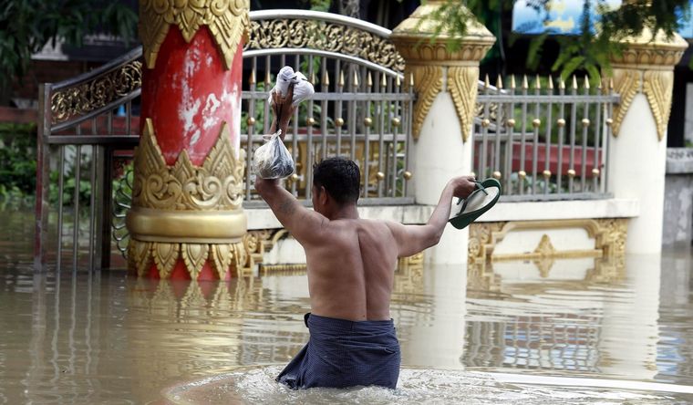 Un hombre carga comida mientras avanza entre las inundaciones en Myanmar. Foto: Efe.