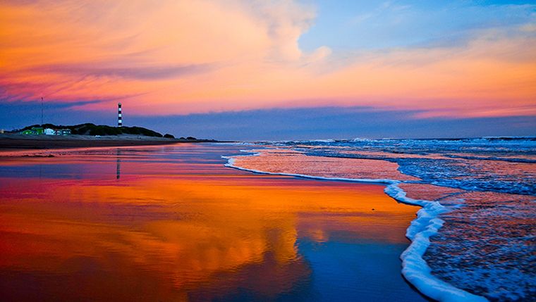 La playa del pueblo de Claromecó capturada al atardecer reflejando la luz sobre la arena infinita del Atlántico. &nbsp;