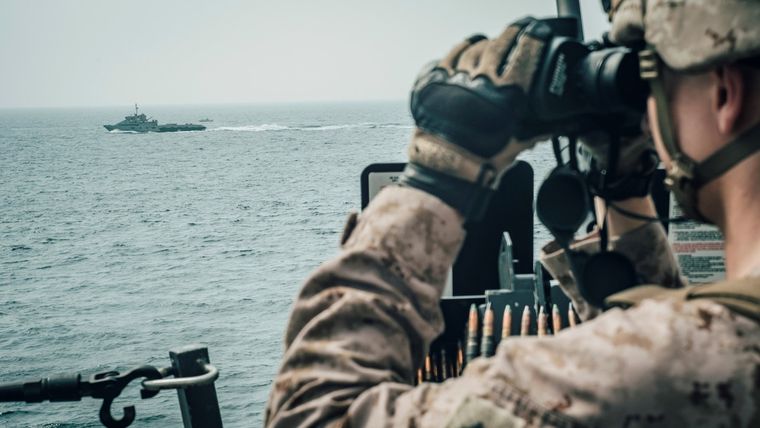 Un marine a bordo del buque USS John P. Murtha observa una embarcación iraní de ataque rápido en el estrecho de Ormuz, frente a Omán, 18 de julio de 2019.