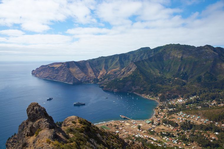 Vista panorámica de la bahía de San Juan Bautista, el poblado principal de la Isla Robinson Crusoe, rodeado por montañas verdes y un mar de aguas profundas.