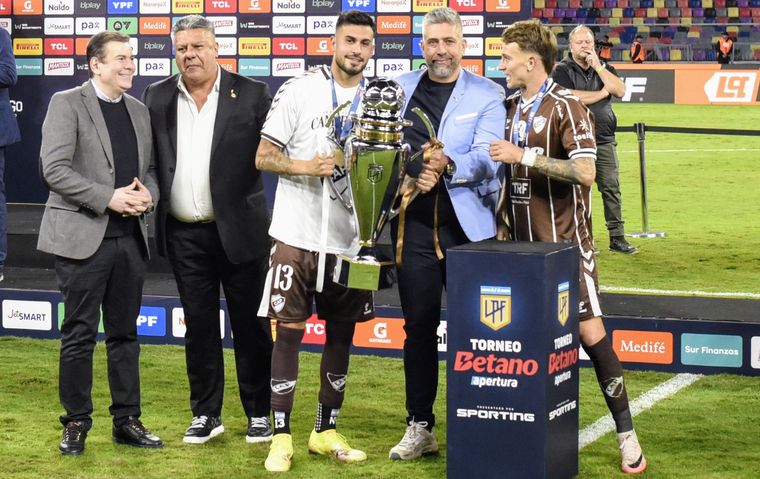 Nacho Vázquez, capitán de Platense, y Guido Mainero, autor del gol del título, reciben la Copa de la Liga junto al presidente Sebastián Ordóñez. A un costado, Chiqui Tapia.&nbsp;