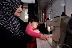 Kalbinur, fotografiada con su hijo Merziye, cose ropa para mantener a su familia