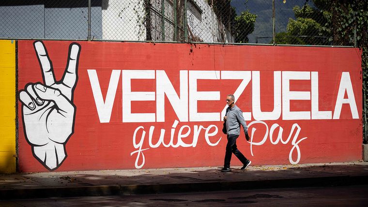 Una persona camina frente a un mural por la Paz en Caracas. Una persona camina frente a un mural por la Paz en Caracas.