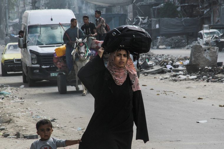 Una mujer palestina desplazada, que huyó de Jabalia después de que el ejército israelí pidiera a los residentes que evacuaran, lleva sus pertenencias en la cabeza mientras se dirige hacia la ciudad de Gaza, en medio del actual conflicto entre Israel y Hamás Foto: Reuters