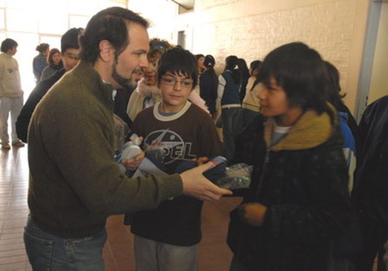 Racconto entrega un par de alpargatas y medias a una adolescente. Foto: Prensa Senado