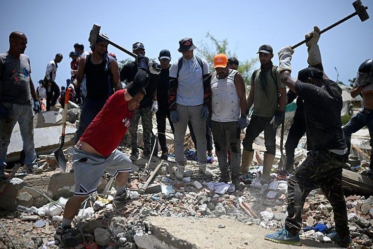 Voluntarios golpean restos de concreto con mazos de hierro buscando sobrevivientes bajo los escombros.