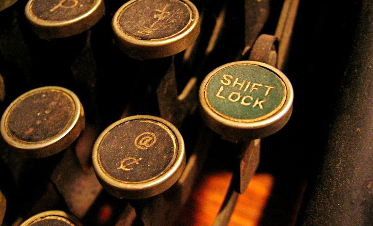 Viene de las máquinas de escribir: al 'cambiar' la posición del mecanismo, permitía imprimir mayúsculas y símbolos. Viene de las máquinas de escribir: al 'cambiar' la posición del mecanismo, permitía imprimir mayúsculas y símbolos.