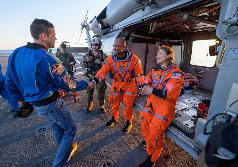 Los astronautas Victor Glover, piloto de Artemis II (izq.), y Christina Koch, especialista de la misión, bajaron del helicóptero con amplias sonrisas.