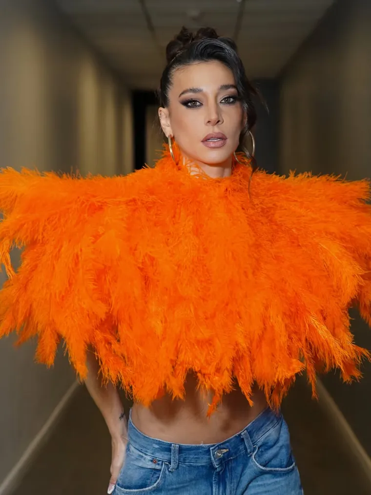 La prenda clásica equilibró el crop top de plumas naranjas. La prenda clásica equilibró el crop top de plumas naranjas.