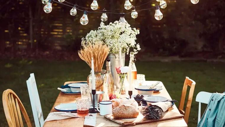 Para colgar guirnaldas de luces sobre un comedor al aire libre hay que utilizar postes y ganchos de madera para poder colocarlas con precisión sobre la mesa. Foto: Lights4Fun