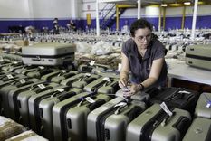 Una trabajadora de la Corte Electoral coloca cintas de seguridad a las maletas que contienen urnas para las elecciones presidenciales de Uruguay. Foto: NA