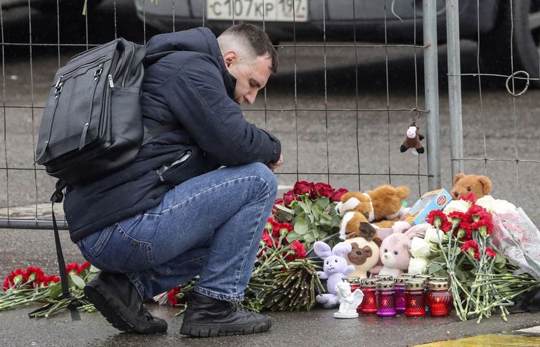 Un hombre dejando flores como símbolo de recuerdo a una de las víctimas frente al teatro en el que ocurrió el atentado. Foto: EFE