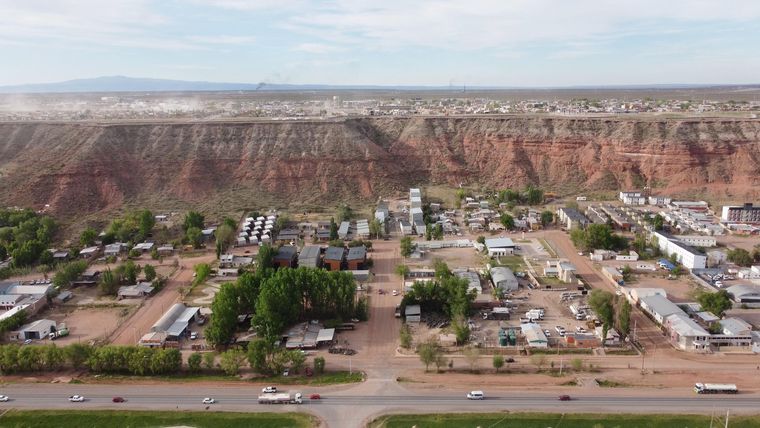 Abajo la ruta y la gomería "El Pampita" rodeada de árboles. Arriba, la meseta, donde se construye la nueva Añelo.