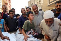 Relatives mourn Palestinian child Saraj Ibrahim. In other photos and video, the man in grey is seen carrying the childs body after a strike hit a water distribution point