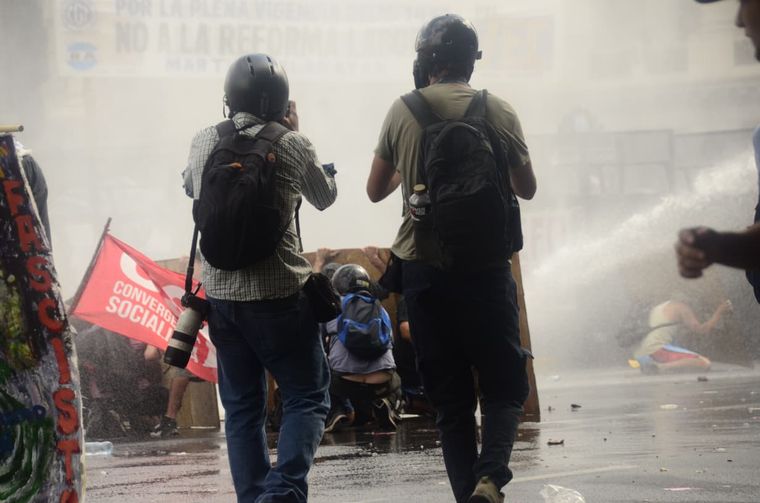Personas detras de tablones y camiones hidrantes, una de las secuencias que dejó la marcha.