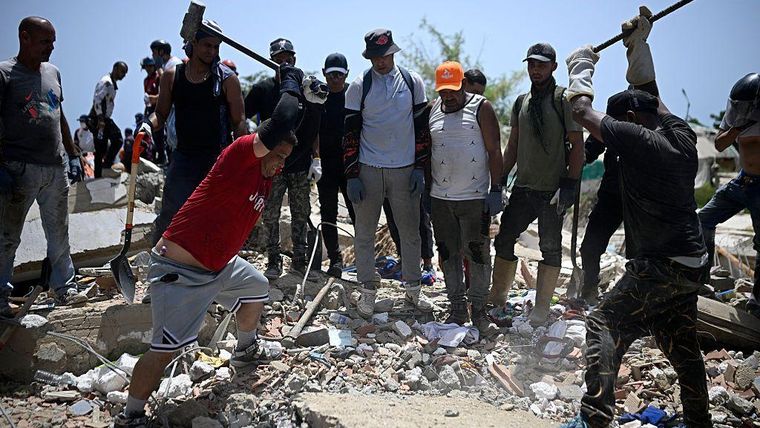 Voluntarios golpean restos de concreto con mazos de hierro buscando sobrevivientes bajo los escombros.