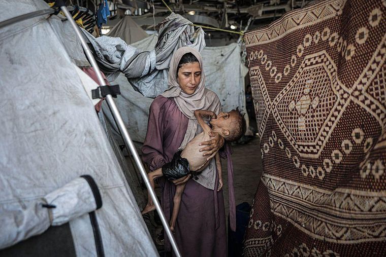 Muhammad Zakariya Ayyoub al-Matouq junto a su madre en una tienda de campaña, en Gaza.