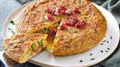 La receta de tortilla paisana nació como una variante campesina de la tortilla española, aprovechando verduras y embutidos disponibles en cada temporada, lo que hace que ninguna receta sea exactamente igual.