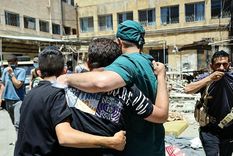 Un médico y otros hombres caminan junto a los cadáveres de los muertos en los combates en un hospital de la ciudad de Suweida.