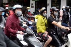 Luz verde para la vuelta a la normalidad: ciudadanos de Hanoi esperan en sus motonetas el cambio de luz.
