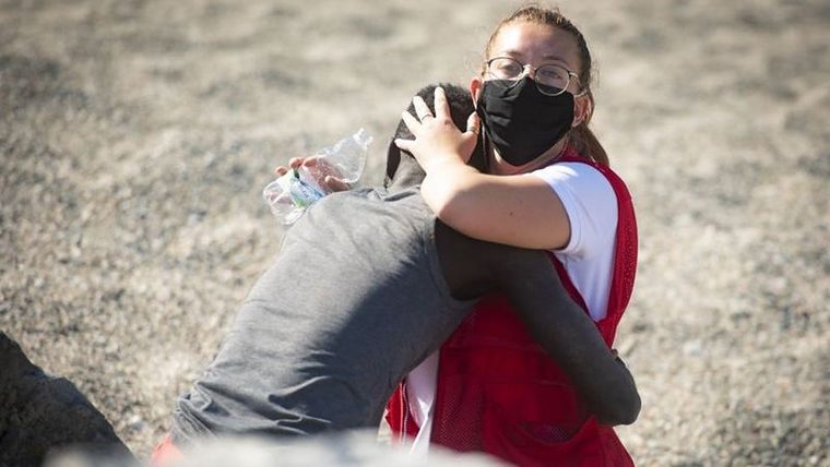 En esta foto, del 18 de mayo, capturada por Marcos Moreno, se ve a Luna Reyes, voluntaria de la Cruz Roja, brindándole ayuda al inmigrante que acababa de salir del mar. Foto: MARCOS MORENO/ANADOLU AGENCY VIA GETTY IMAGES