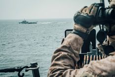 Un marine a bordo del buque USS John P. Murtha observa una embarcación iraní de ataque rápido en el estrecho de Ormuz, frente a Omán, 18 de julio de 2019.