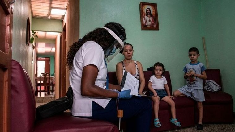 Una trabajadora del sector de la salud le daba información, en julio de 2020, a una familia sobre la prueba de detección de covid-19, en su hogar. Foto: EZEQUIEL BECERRA/AFP VIA GETTY IMAGES