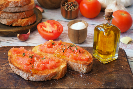 La receta de pan tumaca nació en Cataluña a principios del siglo XX, cuando los campesinos frotaban tomates maduros en el pan duro para ablandarlo y aprovechar los ingredientes disponibles.