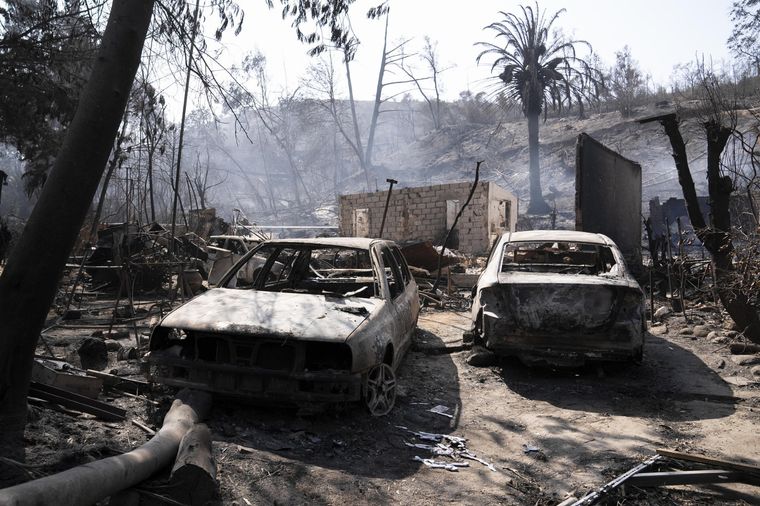 Dos autos calcinados forman parte de los innumerables daños ocasionados por los incendios forestales en Chile. Foto: EFE