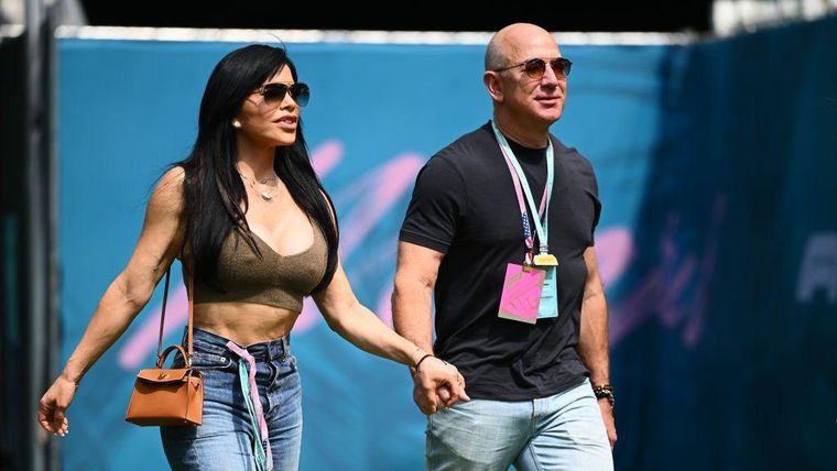 Lauren Sanchez y Jeff Bezos caminan tomados de la mano en un evento deportivo en Miami en 2024.