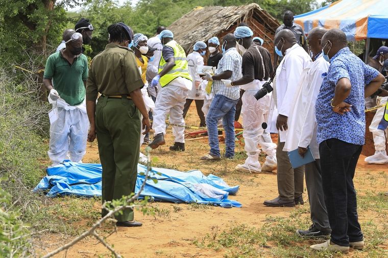 Detectives de homicidios de Kenia y expertos forenses de la Dirección de Investigaciones Criminales (DCI), examinan los cuerpos exhumados de varias fosas comunes poco profundas de presuntos miembros de un culto cristiano después de morirse de hambre. Foto: EFE/EPA/STR