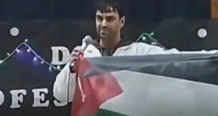 El docente con la bandera de Palestina en el acto por el Día del Maestro.