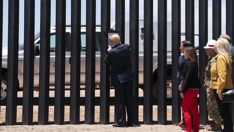El presidente Donald Trump pone su firma en una parte del muro fronterizo durante un recorrido en San Luis, Arizona, el 23 de junio de 2020.
