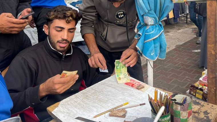 Baraa Abu al-Aoun repara los billetes desgastados que circulan por las calles de Gaza.